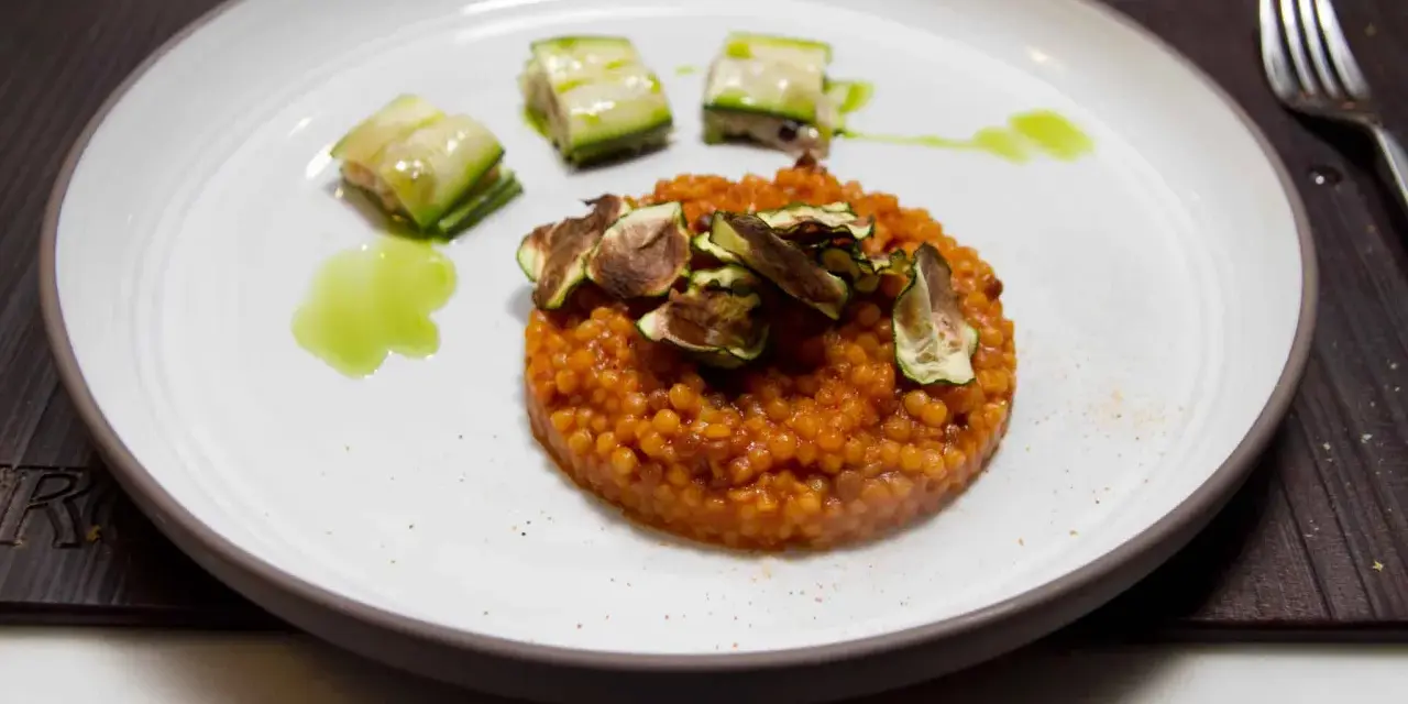 Piatto di fregola sarda ricette con zucchine croccanti e salsa verde. Un primo piatto gustoso e colorato.