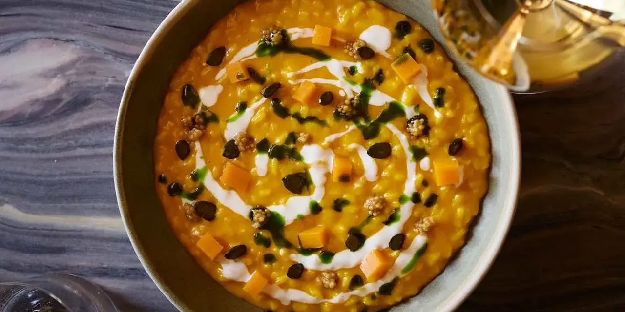 Risotto cremoso alla zucca Hokkaido, guarnito con cubetti di zucca, semi tostati e un filo di panna. Un'idea per le tue ricette zucca hokkaido.