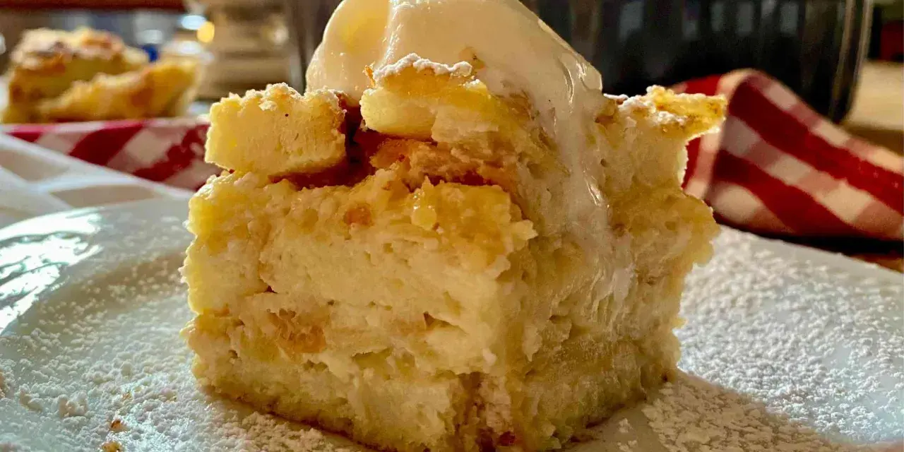 Una fetta di torta di pane raffermo mele e uvetta, cosparsa di zucchero a velo e sormontata da una pallina di gelato.