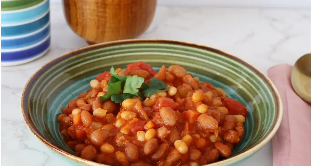 Un piatto invitante di fagioli in umido, con pomodoro e prezzemolo fresco, pronto per essere gustato.