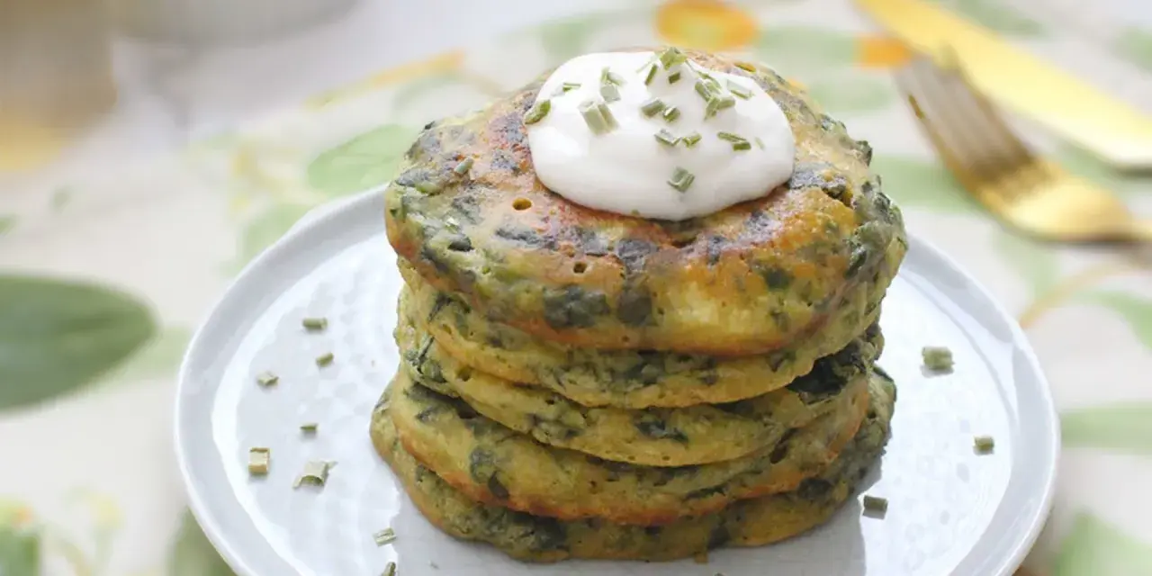 Pancakes salati con farina di grano saraceno e spinaci, guarniti con panna acida e erba cipollina. Un'idea gustosa per le tue ricette con farina di grano saraceno.