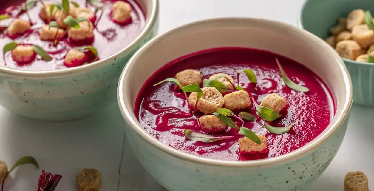 Zuppa cremosa di barbabietola rossa, guarnita con crostini e germogli. Un'idea per le tue barbabietola rossa ricette.