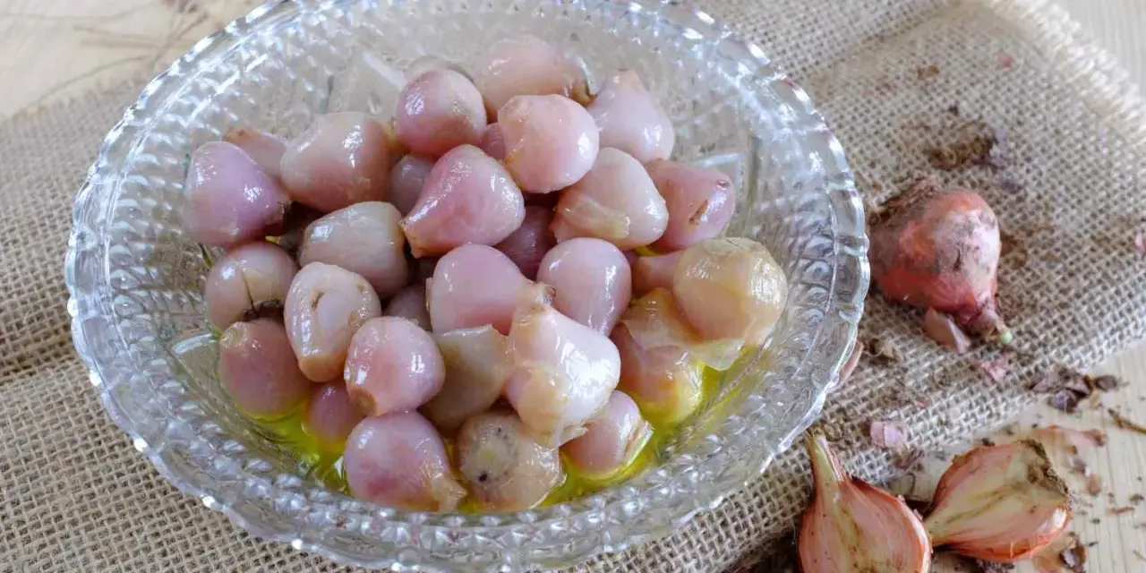 Lampascioni, piccoli bulbi rosa in una ciotola di vetro, sono un sapore pugliese da scoprire.
