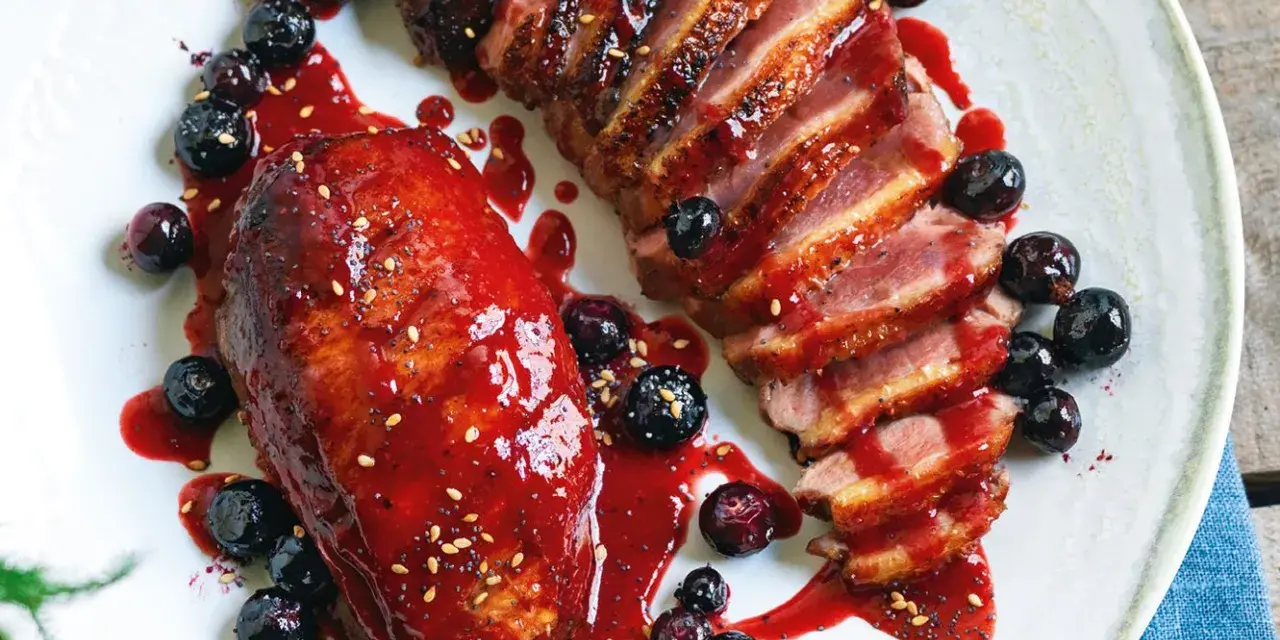 Petto d'anatra ricette: succulento petto d'anatra affettato, glassato con salsa ai frutti di bosco e guarnito con mirtilli freschi.