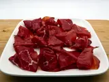 Fette di bresaola, la bresaola che carne è, su un piatto bianco.