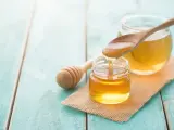 Miele dorato gocciola da un cucchiaio in un vasetto. Nonostante il miele scade raramente, questo nettare è un piacere visivo.
