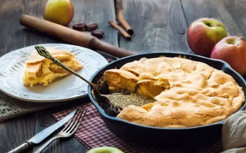 Torta di mele in padella in 10 minuti: soffice e dorata, pronta per essere gustata. Una fetta invitante su un piatto bianco.