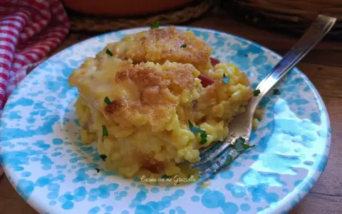 Sformato di riso dorato e filante, servito su un piatto con decorazioni blu. Un piatto invitante e gustoso.