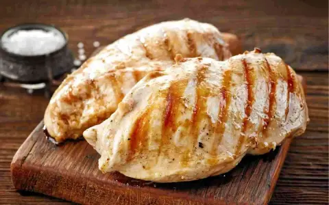 Petto di pollo grigliato, perfetti secondi di carne da preparare in anticipo. Un contorno di sale completa l'immagine.