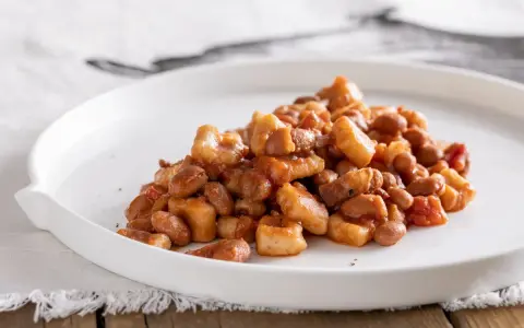 Un piatto di pisarei piacentini, pasta fatta in casa con fagioli e pomodoro, un assaggio della ricetta originale.