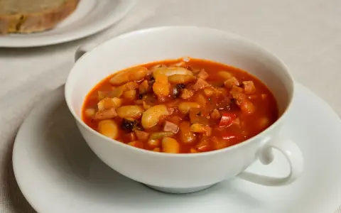 Fagioli in umido, una ricetta veneta saporita con fagioli bianchi, pancetta e pomodoro, serviti in una ciotola bianca.