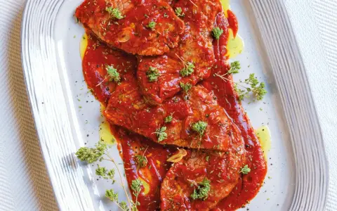 Bistecche alla pizzaiola succulente, ricoperte da salsa rossa e guarnite con erbe aromatiche fresche.