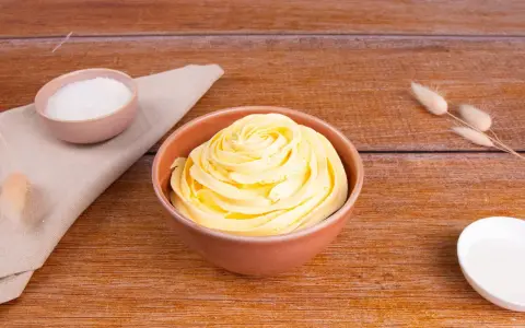 Crema al burro ricetta della nonna, soffice e profumata, pronta per decorare torte. Zucchero e ingredienti in vista.