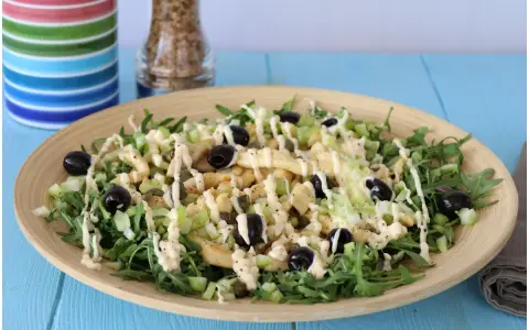 Deliziosa insalata di pollo con rucola, sedano, olive nere e capperi, condita con una cremosa salsa.