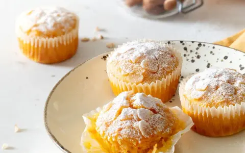 Muffin carote e yogurt spolverati di zucchero a velo e mandorle. Deliziosi e soffici, perfetti per la colazione.