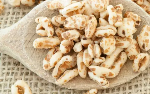 Farro soffiato su un cucchiaio di legno, perfetto per colazioni leggere e ricette creative.