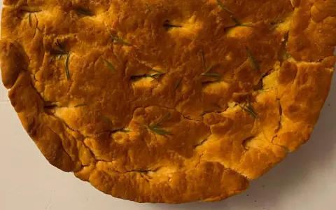 Focaccia di lenticchie dorata e fragrante, con rosmarino fresco che spunta dalla crosta croccante.