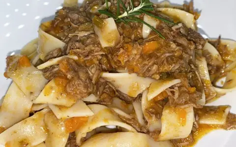 Pappardelle condite con un saporito ragù di cinghiale in bianco, guarnite con rosmarino fresco.