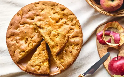 Una deliziosa torta di mele con farina di avena, appena sfornata, con mele fresche e scorze su un tagliere.