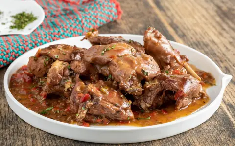 Piatto di coniglio con peperoni rossi e verdi, cotto in umido con erbe aromatiche.