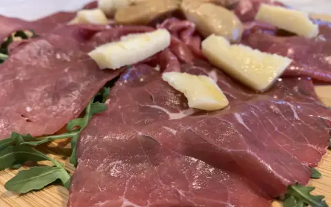 Carne salada cos'è? Fettine sottili di carne rossa, condite con erbe aromatiche e scaglie di formaggio stagionato, su un letto di rucola fresca.