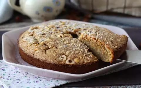 Deliziosa torta di nocciole senza farina, cosparsa di zucchero a velo e nocciole intere. Perfetta per ogni occasione.
