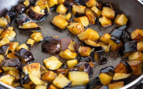 Melanzane a cubetti dorate e caramellate in padella, pronte per uno dei 100 modi per cucinare le melanzane.