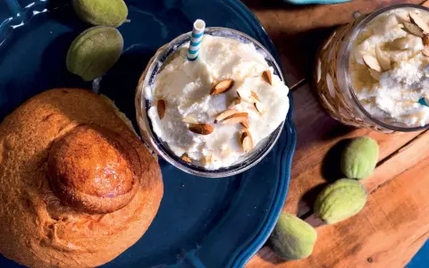 Deliziosa granita di mandorle servita con mandorle a lamelle e pane dolce. Freschezza siciliana in un bicchiere.