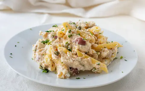 Piatto di pasta cremosa con tonno, capperi e olive taggiasche, guarnito con prezzemolo fresco.