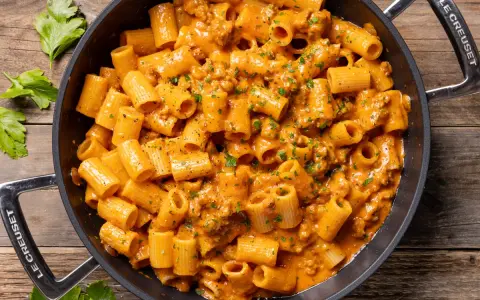 Un invitante piatto di pasta con salsiccia alla napoletana, condita con una cremosa salsa arancione e prezzemolo fresco.