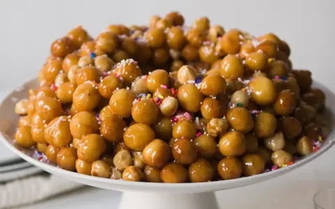 Struffoli ricetta della nonna: palline dorate e lucide, cosparse di zuccherini colorati, un dolce tradizionale che profuma di casa.