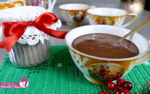 Un vasetto decorato con un fiocco rosso e una tazza piena di cioccolata fatta in casa, pronta per essere gustata.