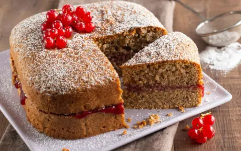 Torta di grano saraceno soffice, farcita con marmellata e decorata con ribes rossi e zucchero a velo.