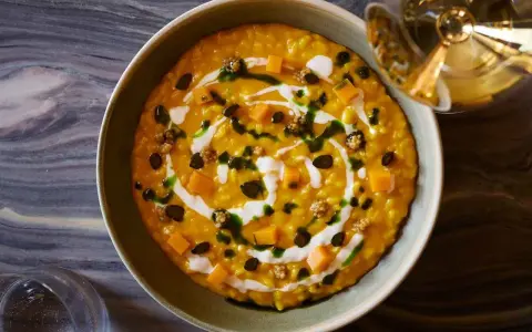 Risotto cremoso alla zucca Hokkaido, guarnito con cubetti di zucca, semi tostati e un filo di panna. Un'idea per le tue ricette zucca hokkaido.