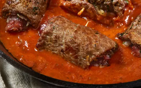 Involtini di carne in padella con sughetto rosso, un piatto succulento e invitante.