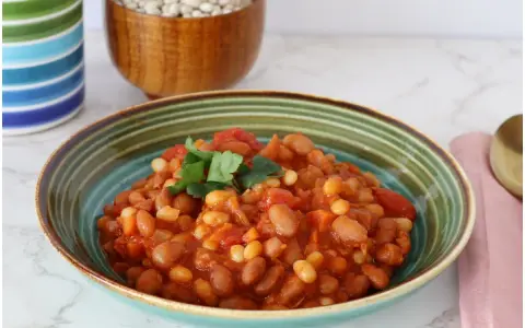 Un piatto invitante di fagioli in umido, con pomodoro e prezzemolo fresco, pronto per essere gustato.