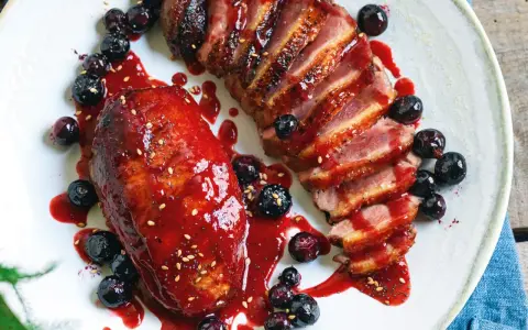 Petto d'anatra ricette: succulento petto d'anatra affettato, glassato con salsa ai frutti di bosco e guarnito con mirtilli freschi.