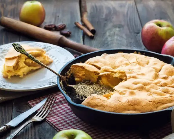 Torta di mele in padella in 10 minuti: soffice e dorata, pronta per essere gustata. Una fetta invitante su un piatto bianco.