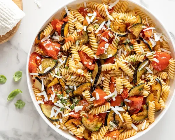 Pasta fredda con melanzane, pomodori e ricotta salata grattugiata. Un'idea perfetta per cosa mettere nella pasta fredda, fresca e saporita.