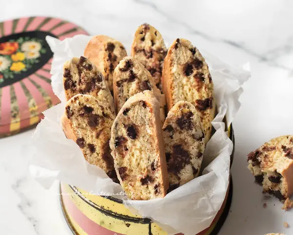 Biscotti con frutta secca, croccanti e golosi, serviti in un contenitore vintage. Perfetti per la colazione o una pausa caffè.