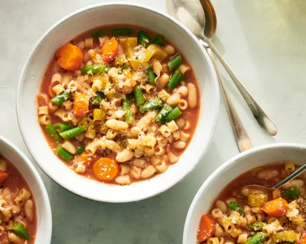 Tre ciotole di fumante pasta e fagioli vegetariana, ricca di verdure e condita con parmigiano.