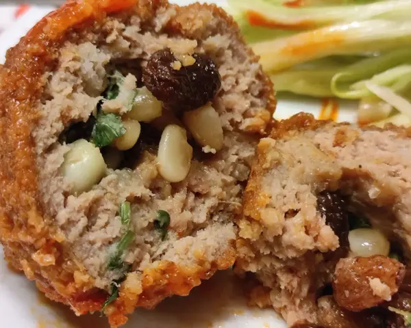 Polpette al sugo napoletane, un abbraccio di carne saporita con pinoli e uvetta, immerse in un sugo rosso invitante.