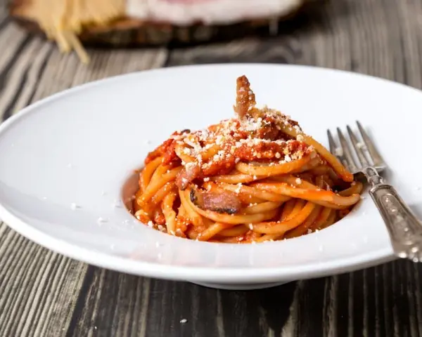 Piatto di spaghetti con sugo rosso, guanciale e formaggio grattugiato. Una gustosa ricetta originale amatriciana cipolla.