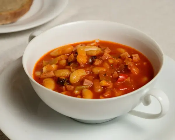 Fagioli in umido, una ricetta veneta saporita con fagioli bianchi, pancetta e pomodoro, serviti in una ciotola bianca.