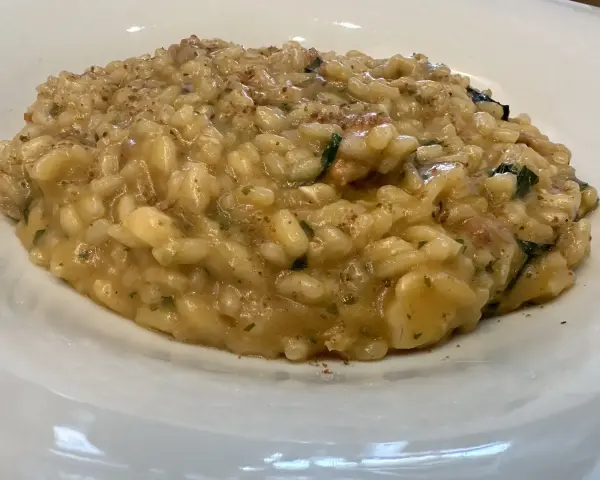 Un cremoso risotto alla pescatora ricetta napoletana, con riso carnaroli e profumi di mare, servito in un piatto bianco.