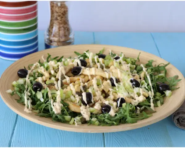 Deliziosa insalata di pollo con rucola, sedano, olive nere e capperi, condita con una cremosa salsa.