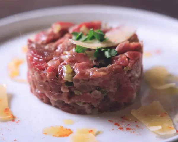 Tartare di manzo, un piatto raffinato. Scopri come condirla per un sapore indimenticabile, con scaglie di parmigiano e un tocco di paprika.