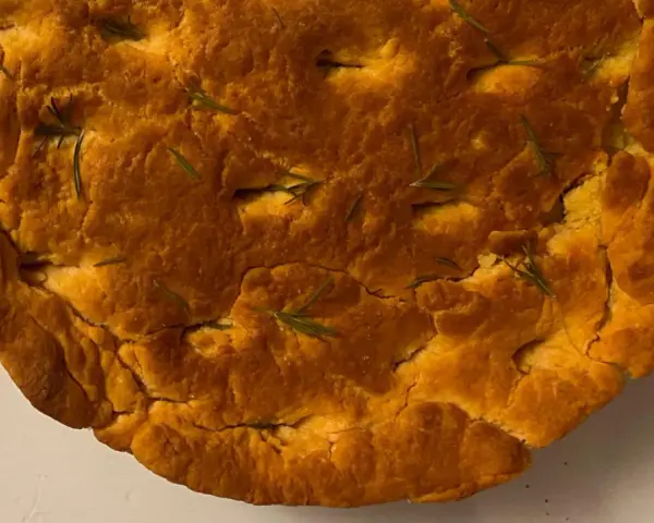 Focaccia di lenticchie dorata e fragrante, con rosmarino fresco che spunta dalla crosta croccante.
