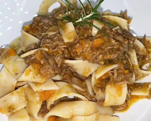 Pappardelle condite con un saporito ragù di cinghiale in bianco, guarnite con rosmarino fresco.