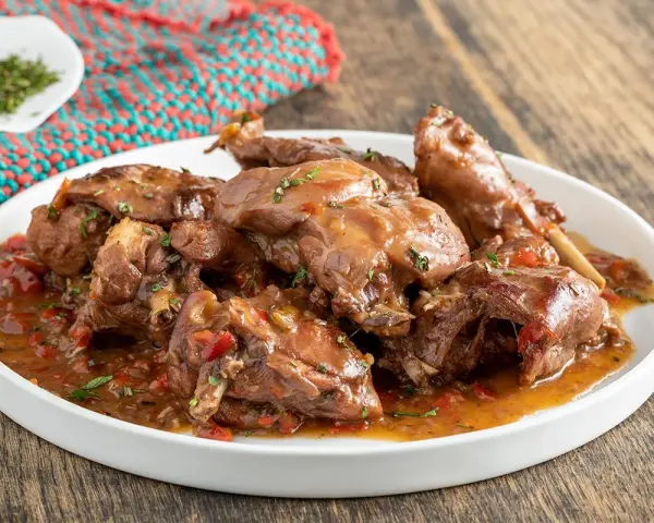 Piatto di coniglio con peperoni rossi e verdi, cotto in umido con erbe aromatiche.